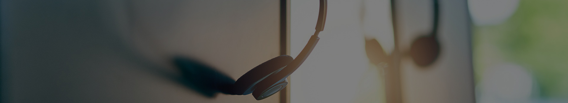 Our call centre can be contacted on.... Closeup shot of a headset hanging on a computer in an office.